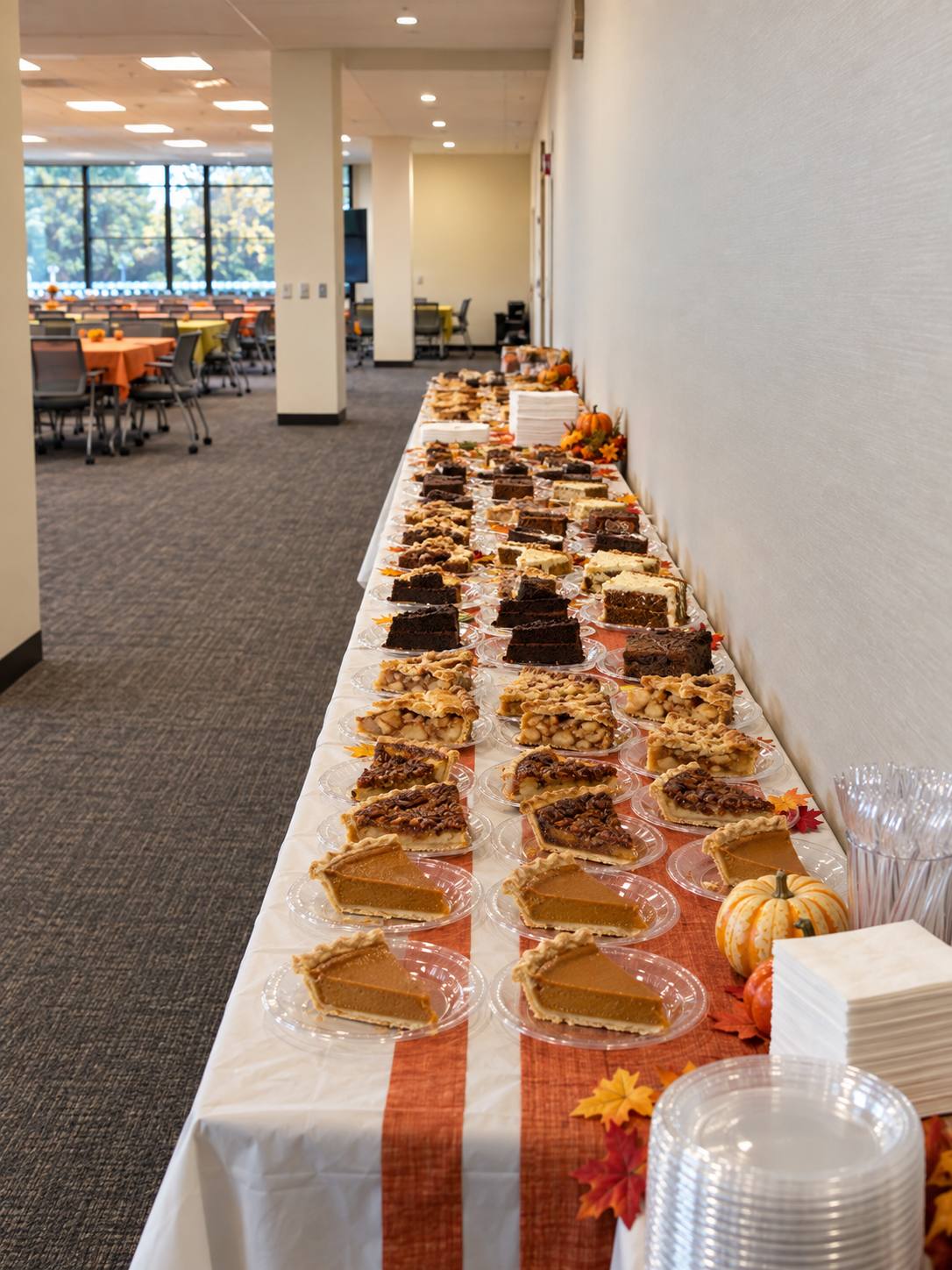 Thanksgiving dessert table at an office catering event with pie slices and cakes